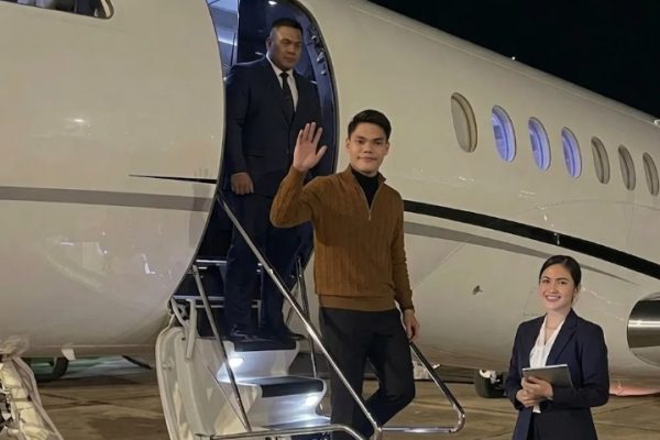 Pengusaha muda tampil percaya diri saat menuruni tangga jet pribadi di bandara pada malam hari.
