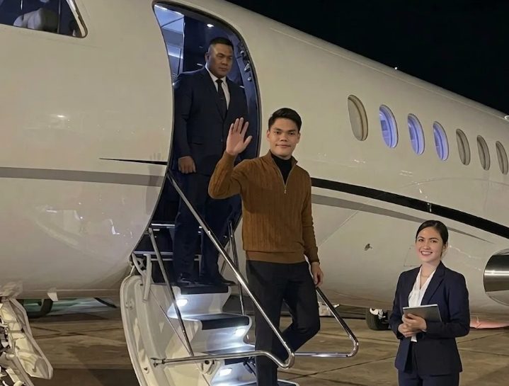 Pengusaha muda tampil percaya diri saat menuruni tangga jet pribadi di bandara pada malam hari.