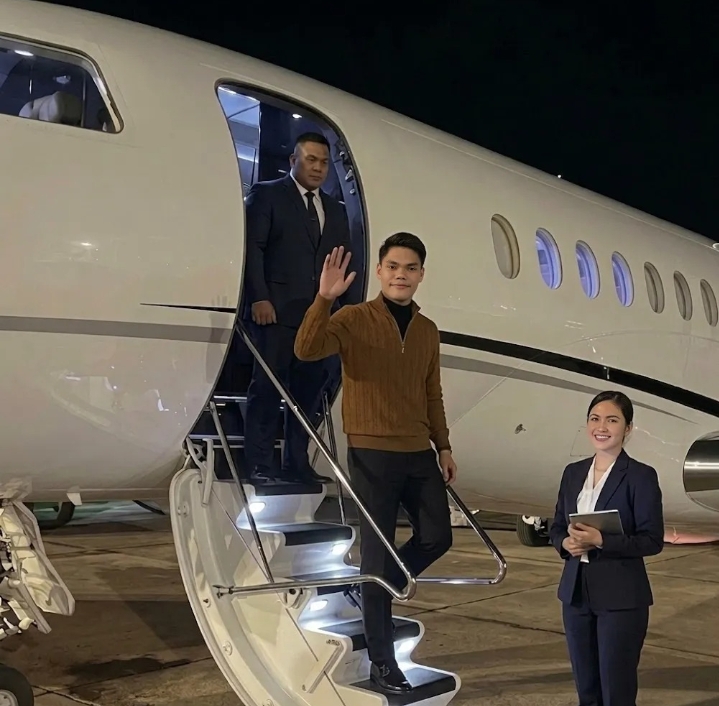 Pengusaha muda tampil percaya diri saat menuruni tangga jet pribadi di bandara pada malam hari.